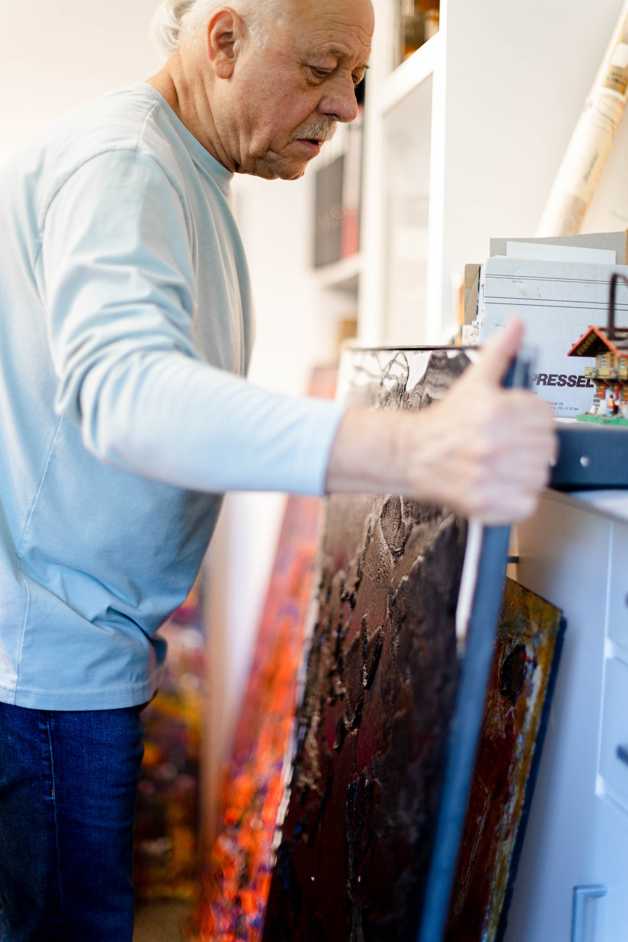 Künstler Harry Bauer in seinem Atelier, in den Händen ein Gemälde.